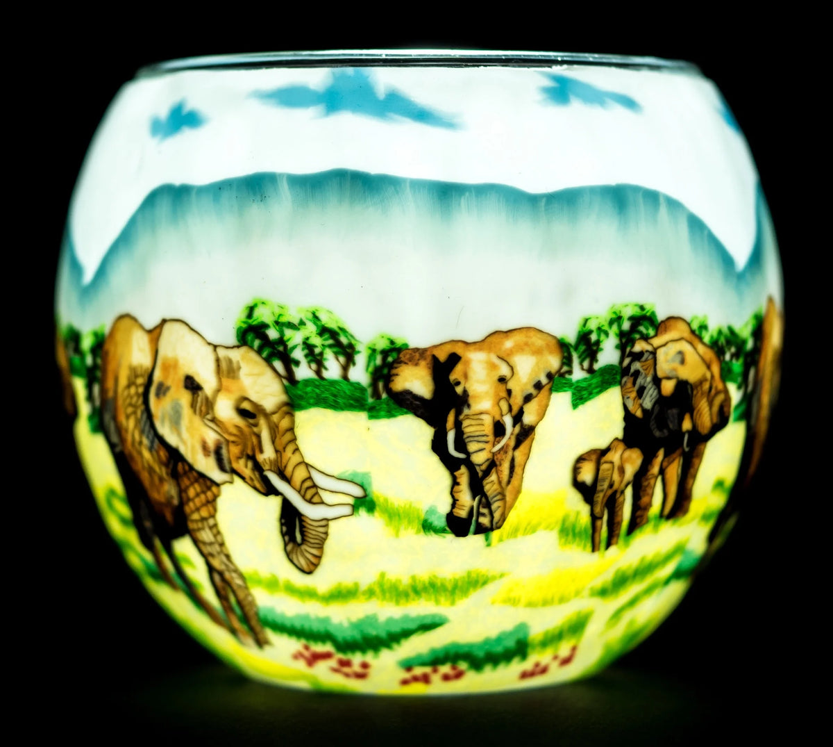 Elephant Family Claymaster light globe glowing from within, showing adult elephants and a calf crossing a savanna with trees and mountains